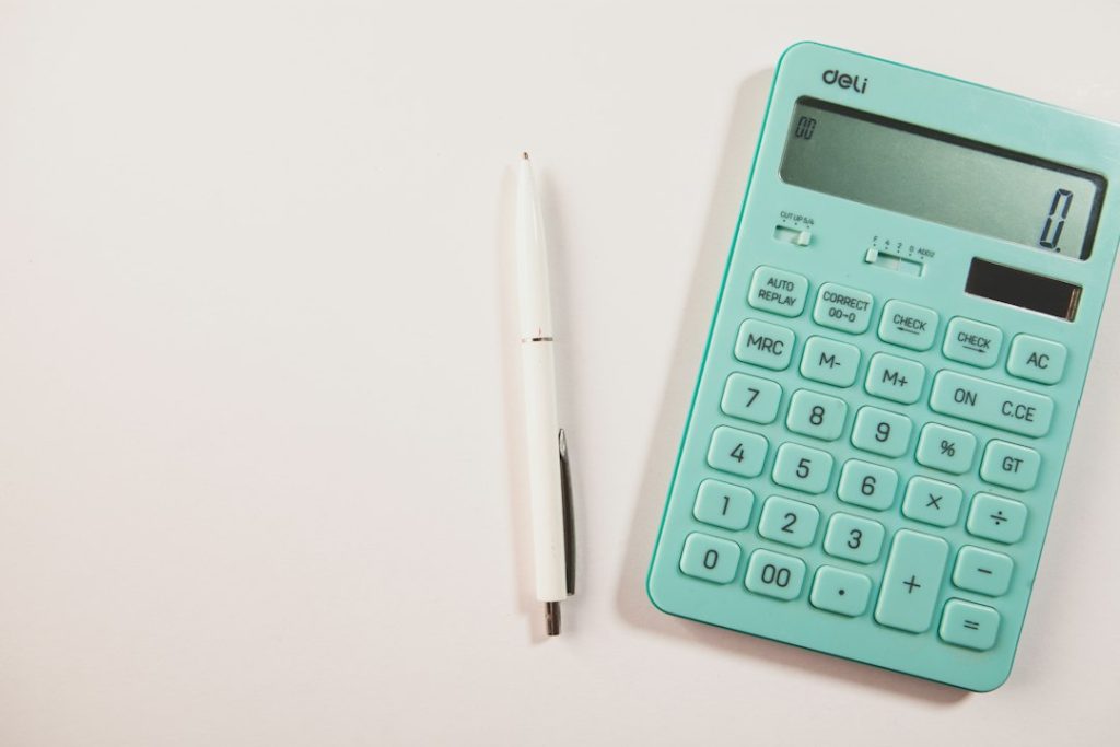 Turquoise calculator and pen on a light desk
